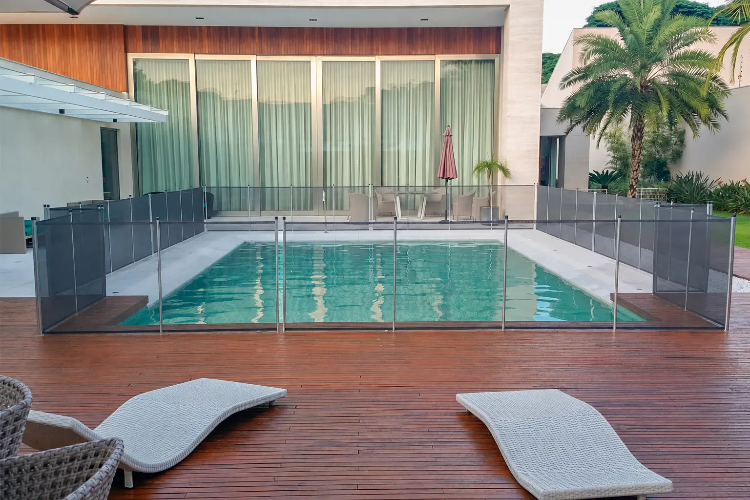 Cerca de proteção cinza com hastes metálicas ao redor de piscina retangular