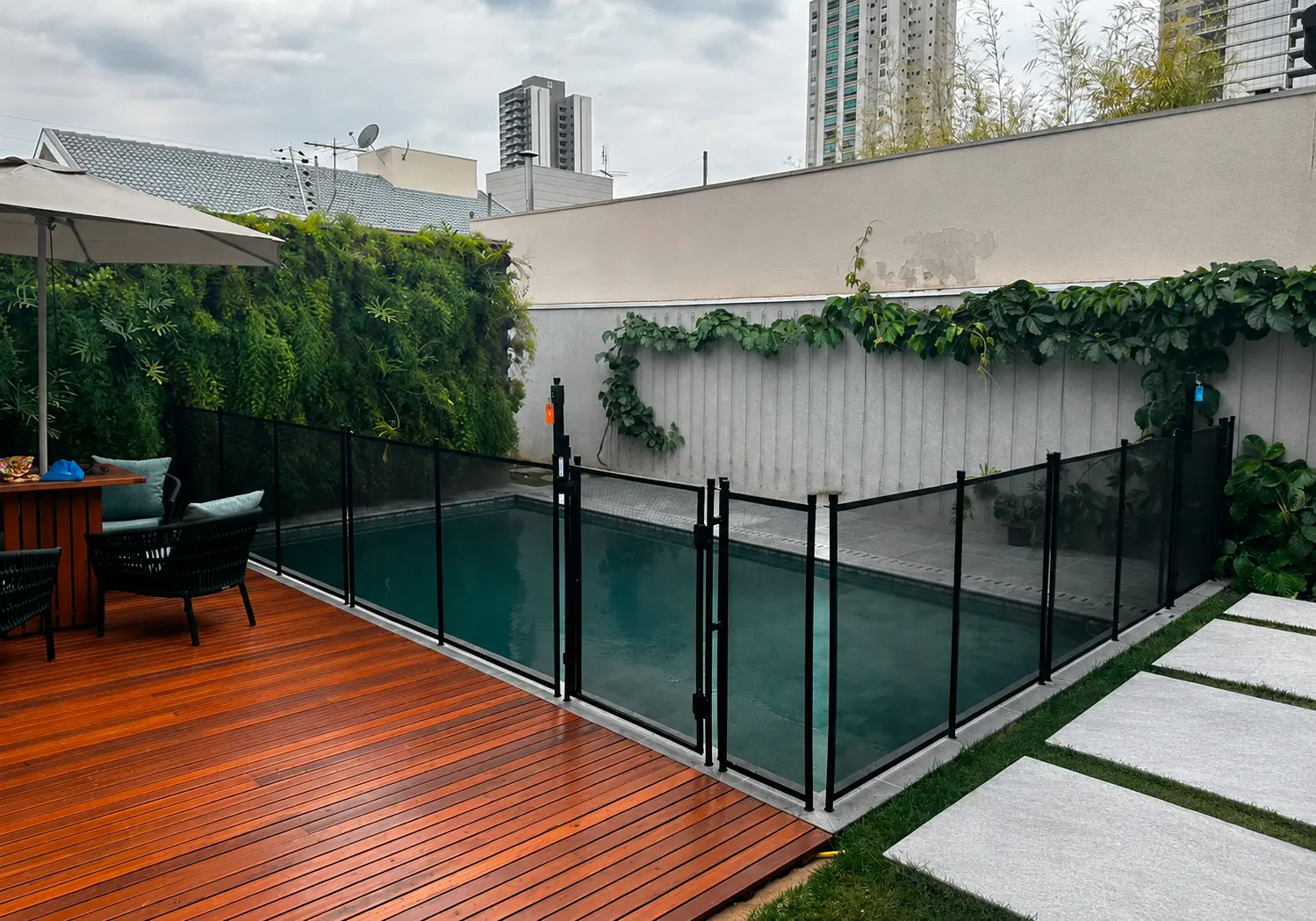 Cerca de proteção preta com portão de acesso ao redor de piscina residencial
